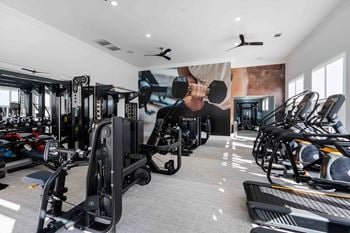 a gym with cardio equipment and a mural of a man holding a dumbbell